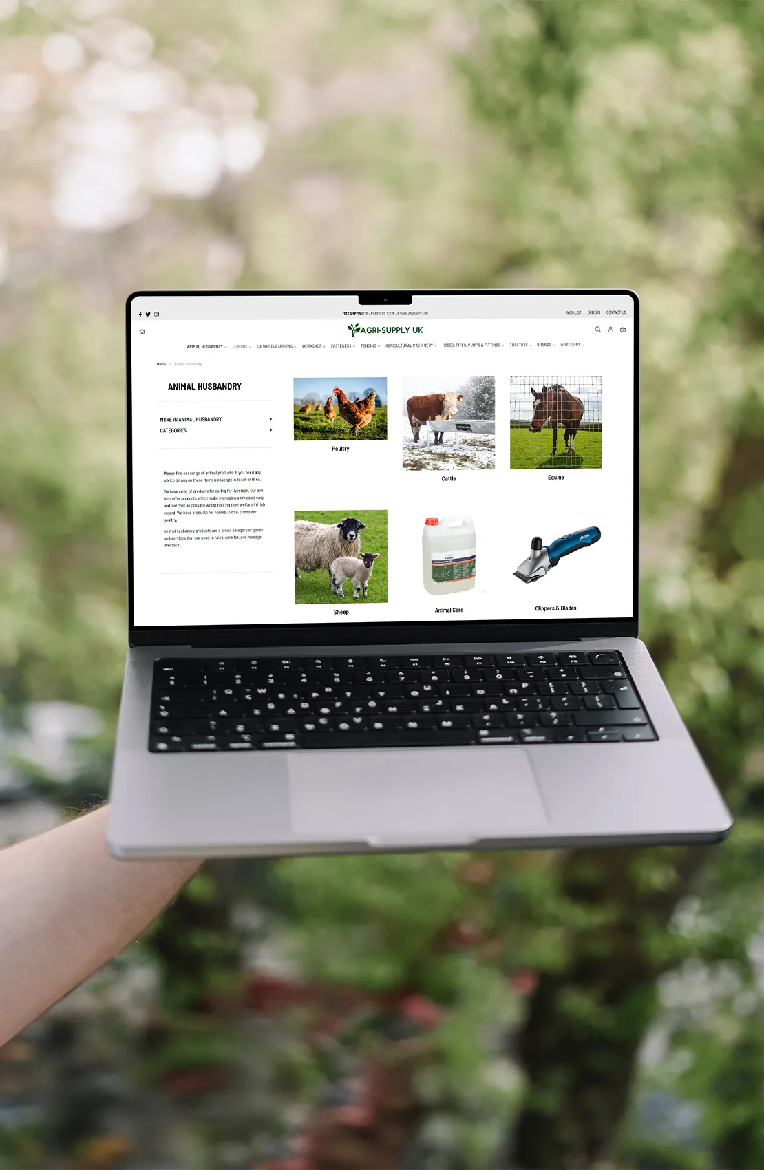 A laptop being held showing the Agri-Supply website homepage