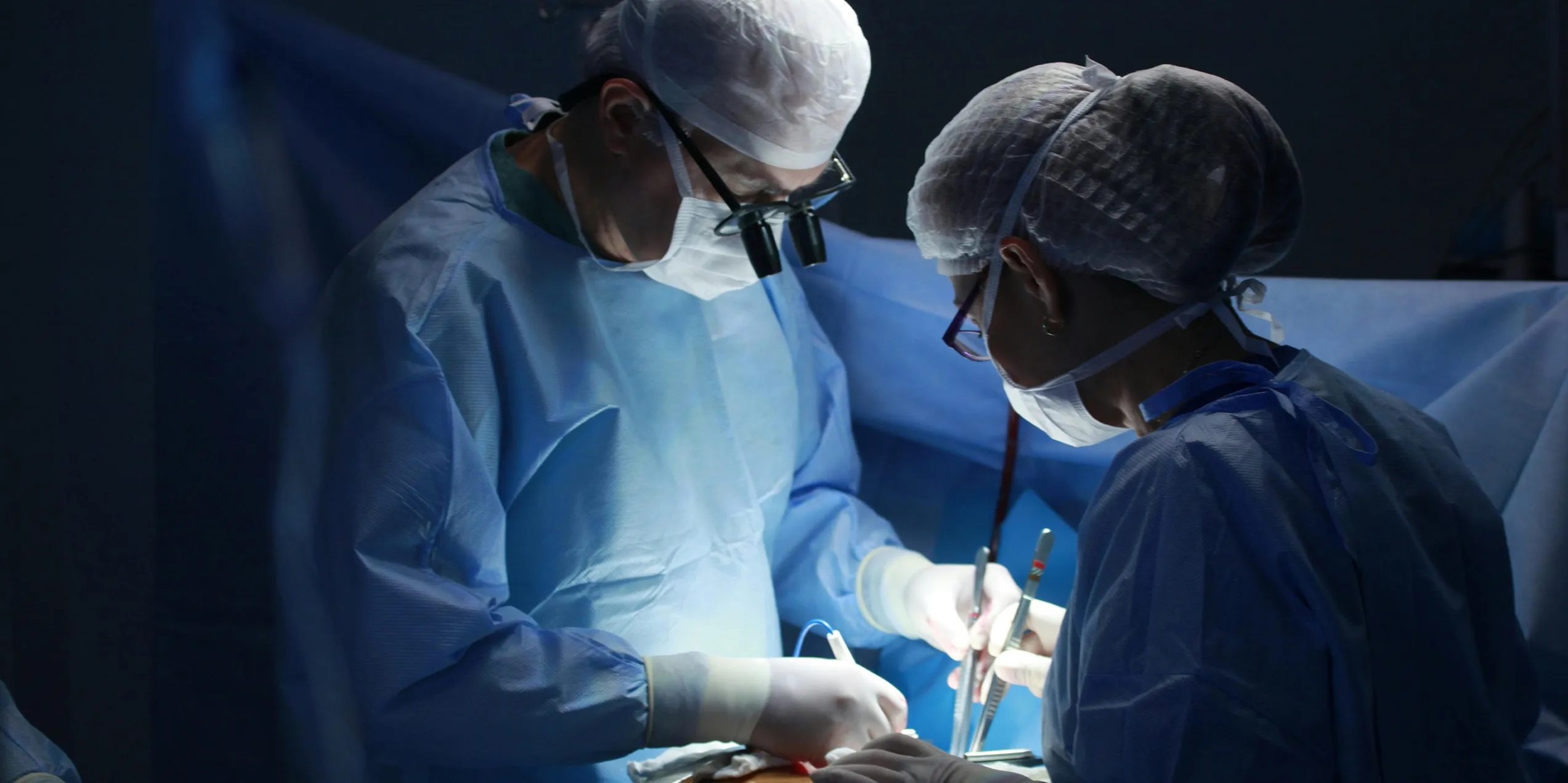 Two people in surgical scrubs in an operating theatre