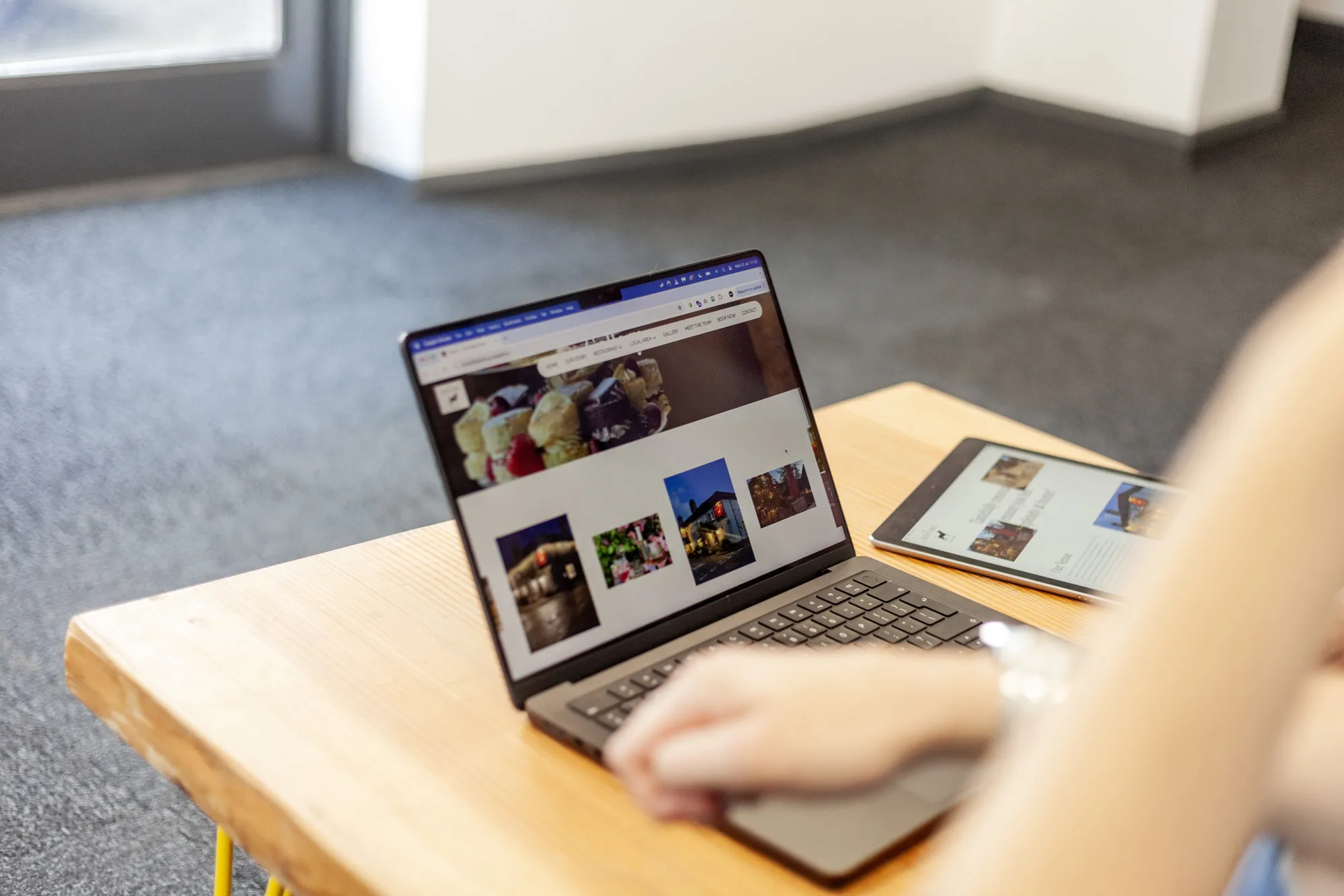 A MacBook on a coffee table showing the Dickin Arms website homepage