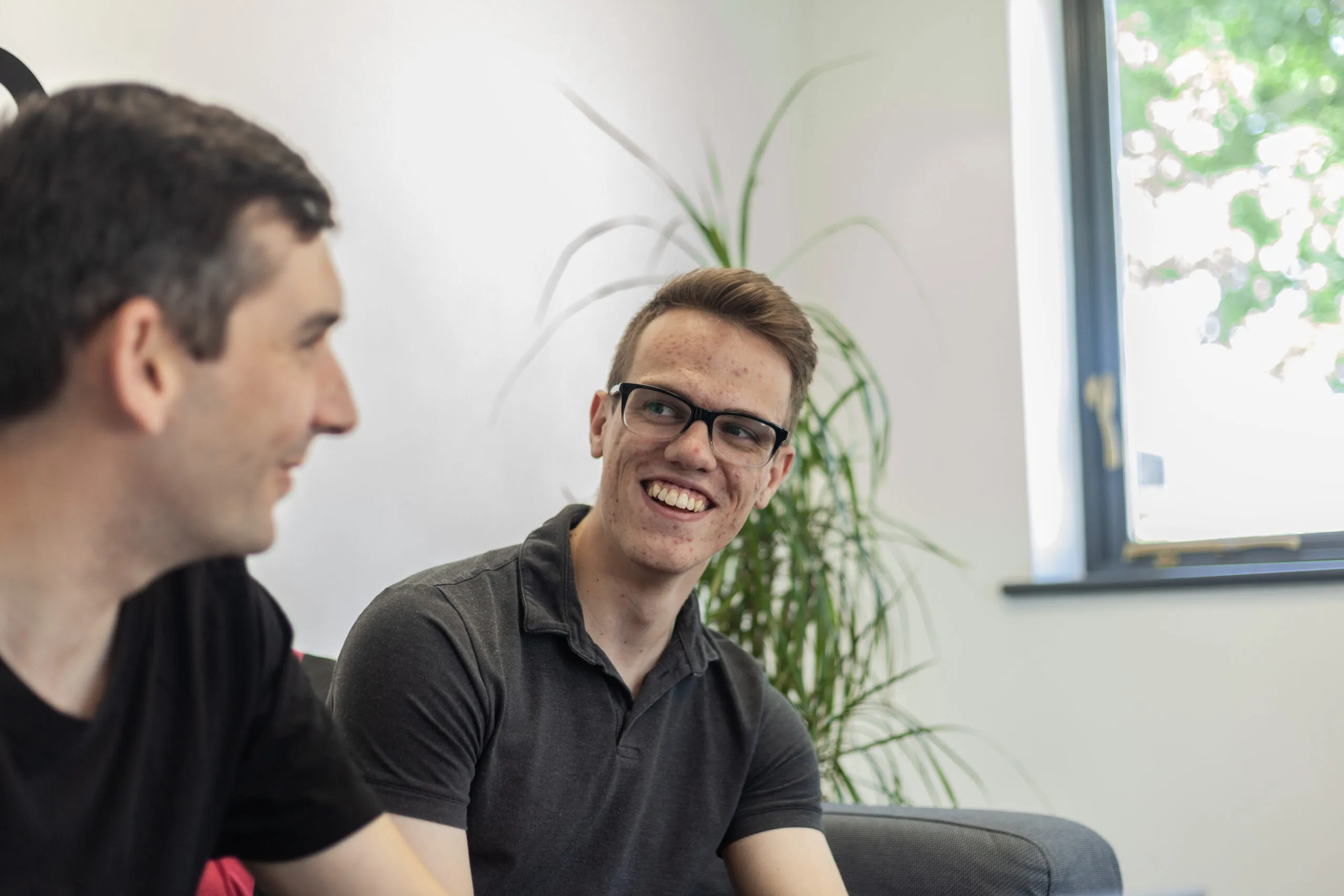 A close up of two men sitting down talking and smiling
