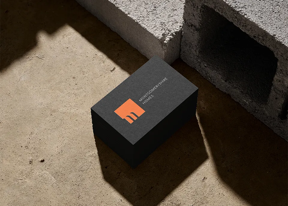 A stack of business cards surrounded by cinder blocks showing the Montgomeryshire Homes logo 