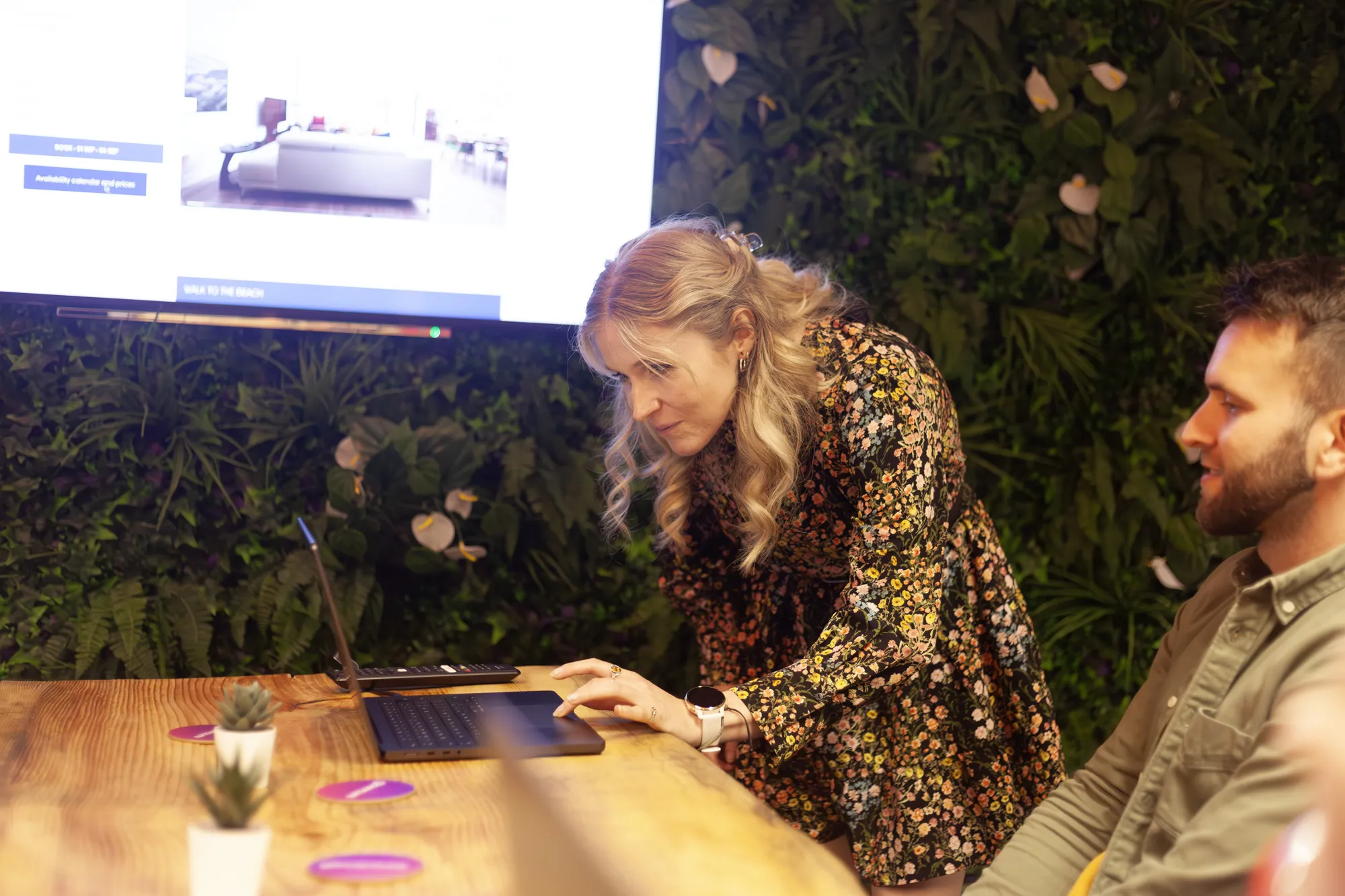 A woman standing over a laptop in a meeting room