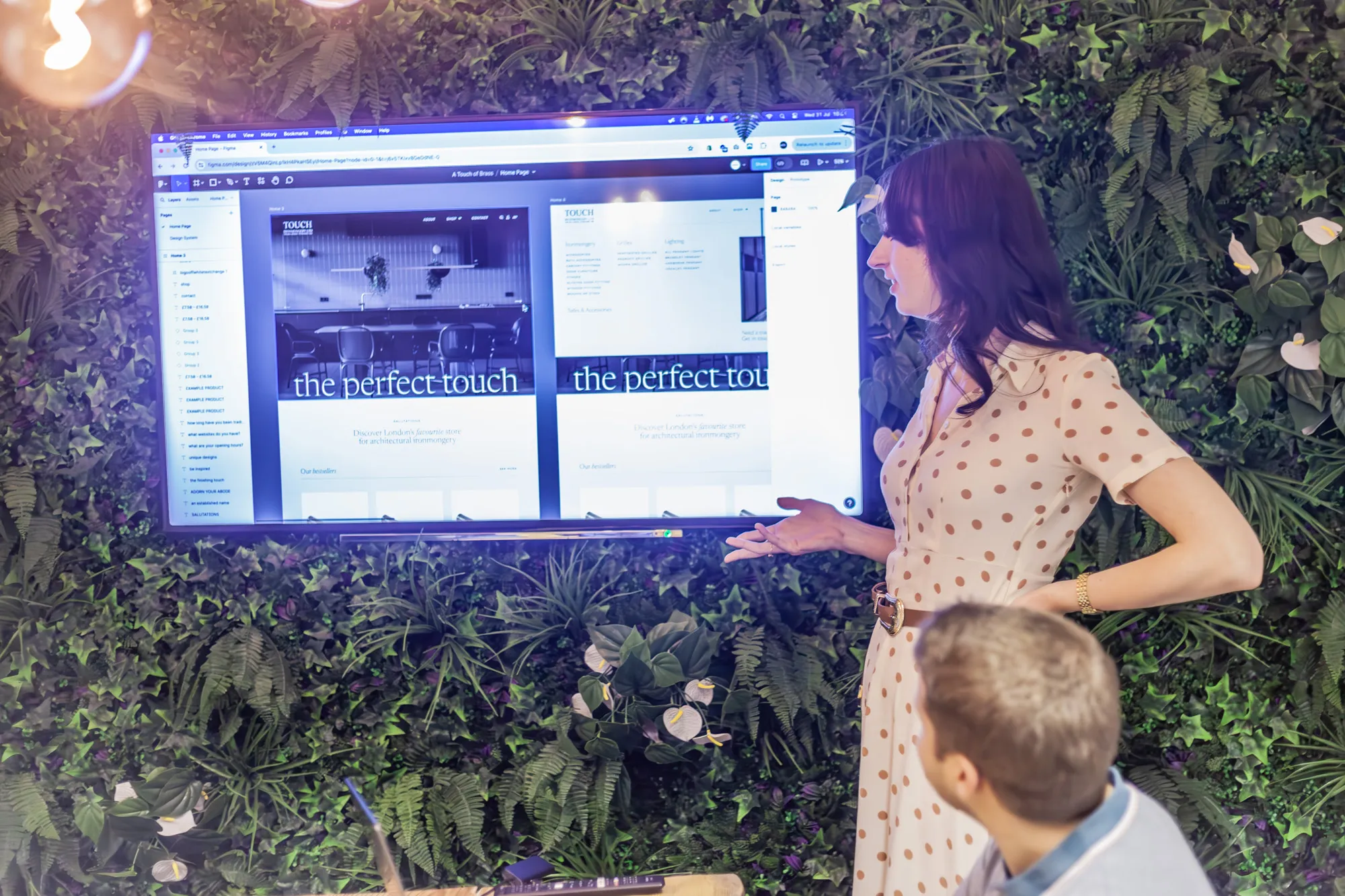 A woman stood in front of a wall mounted TV showing an eCommerce website design