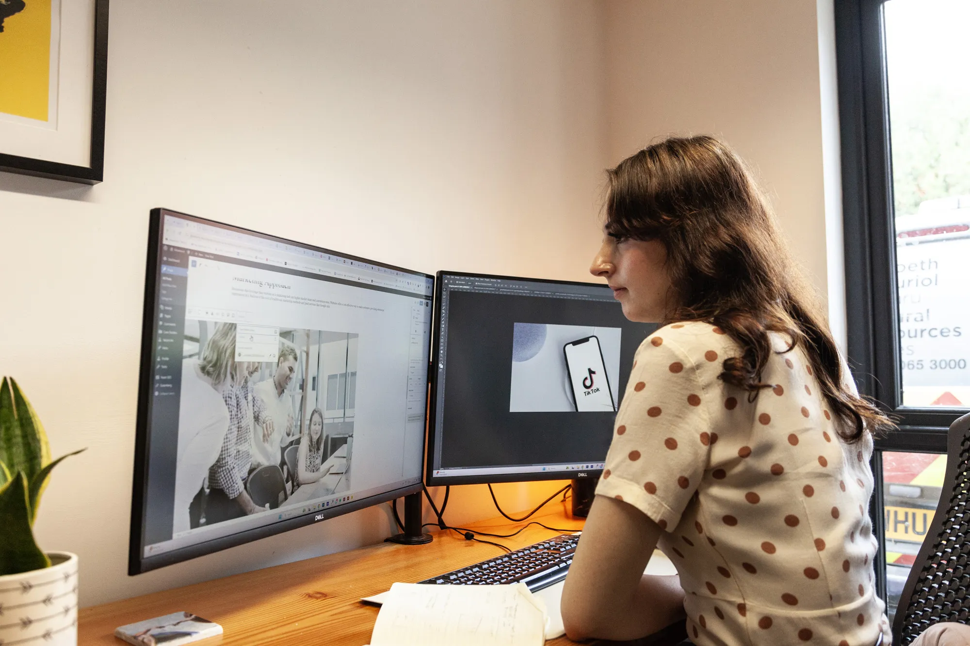 A woman sat at a wooden desk looking at a computer screen