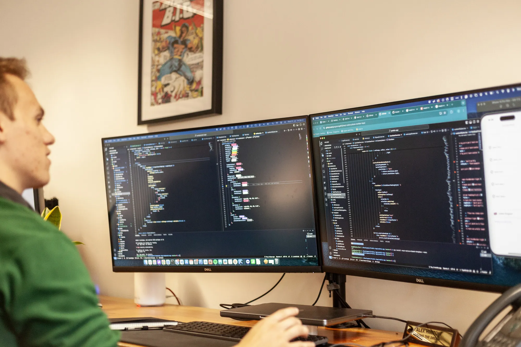 A man sat at a wooden desk looking at a computer screen showing lines of code