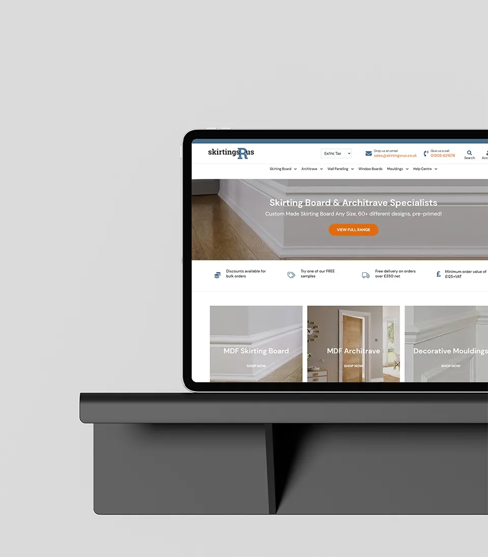 An iPad on a dark grey shelf showing the Skirtings R Us website homepage