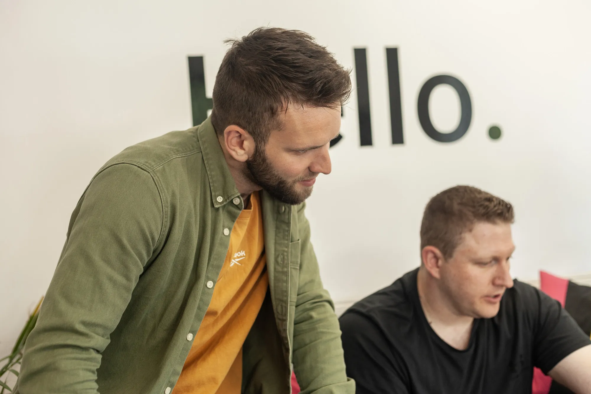 Two men sat on a grey sofa looking on