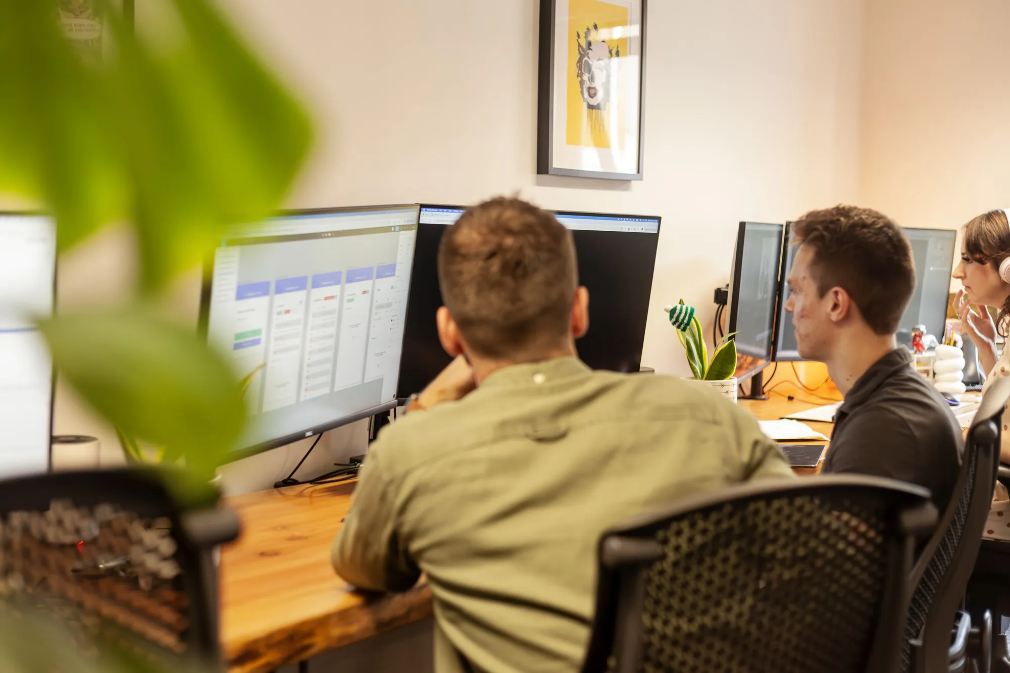 Two men sitting at a wooden desk looking at a computer screen