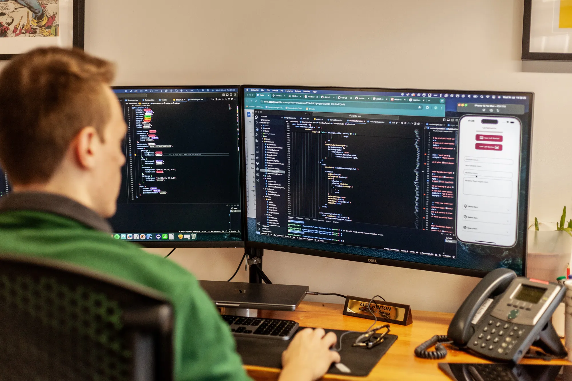 A man sitting at a wooden desk looking at a computer screen with lines of code