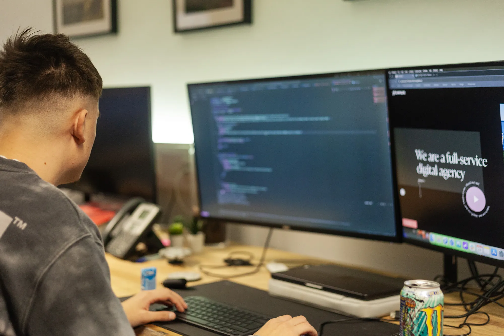 A man sat at desk looking at a two computer screens