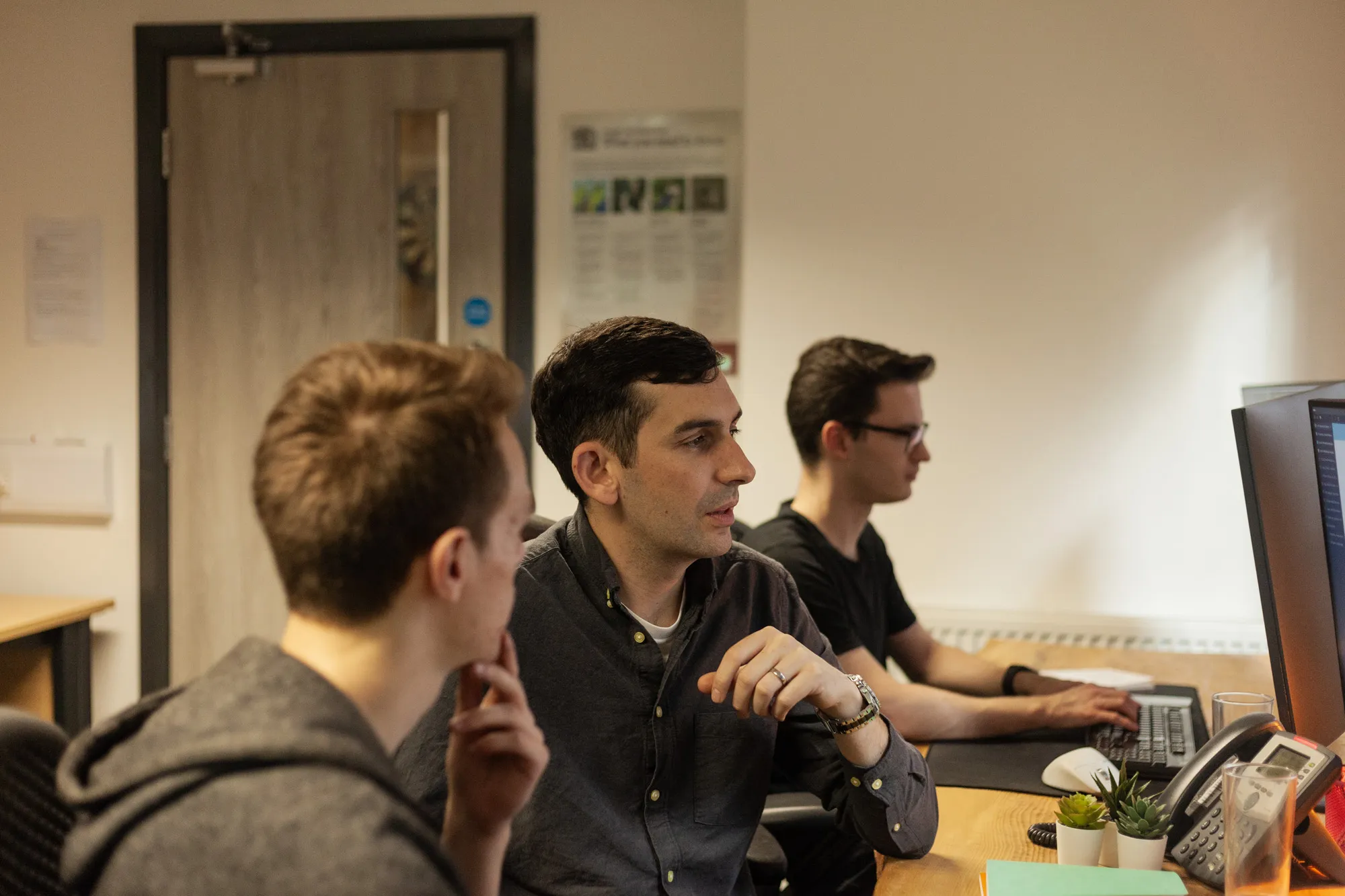 Three men sat in front of computers