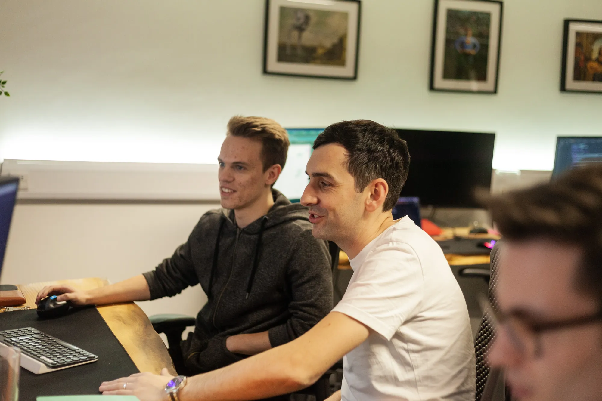 Two men sat at a computer talking and smiling