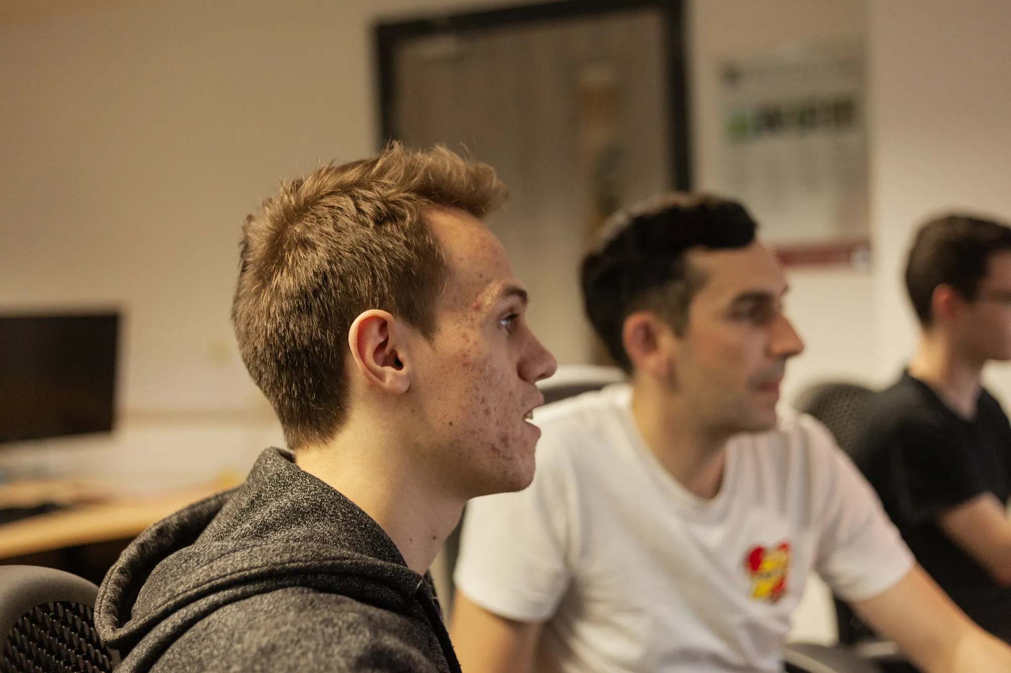 Two men sat at a desk looking towards a computer