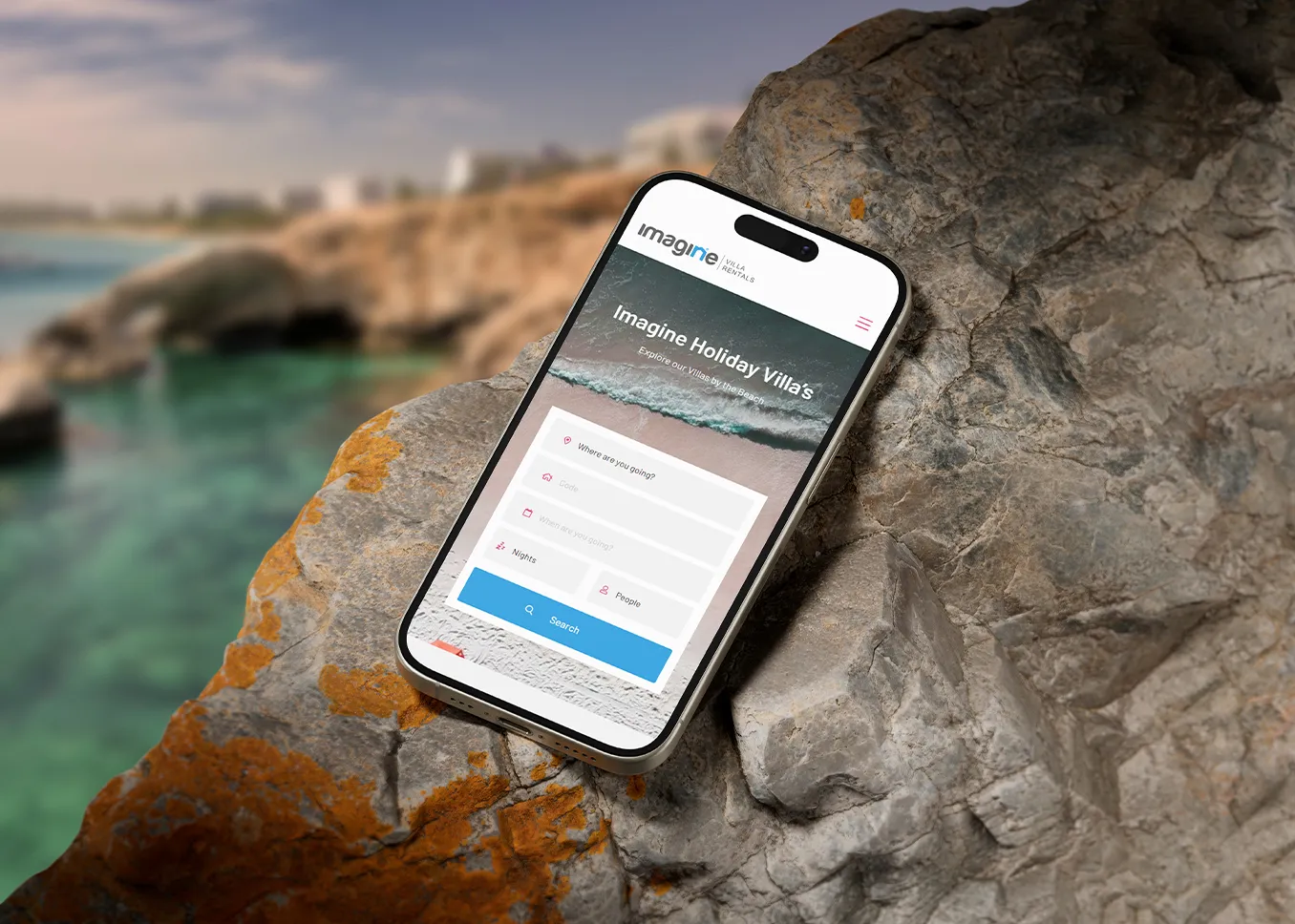 An iPhone on a rock showing the Imagine Villas website homepage
