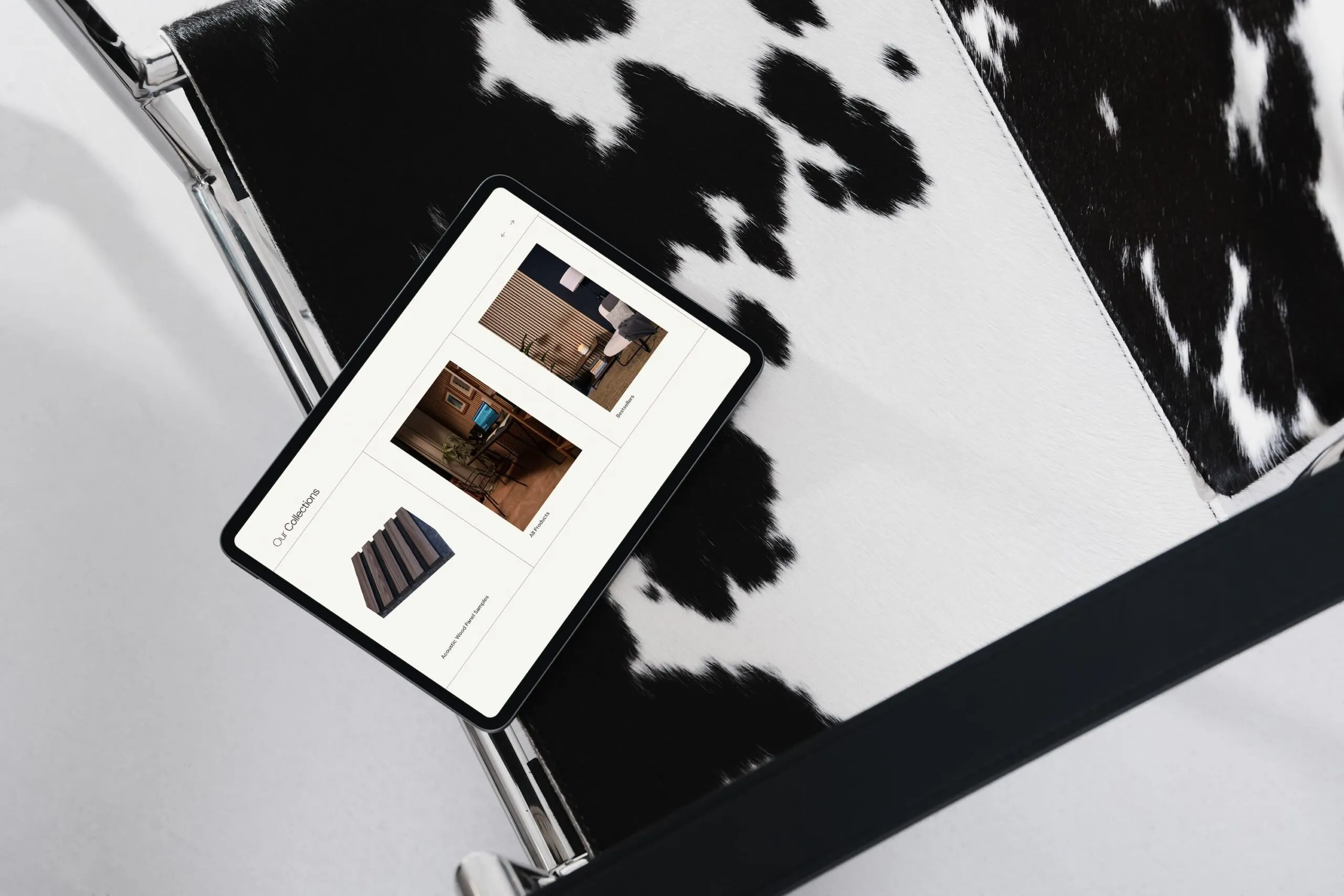 A MaxBook on a cow print chair showing the featured products section from the Opulux Homes website