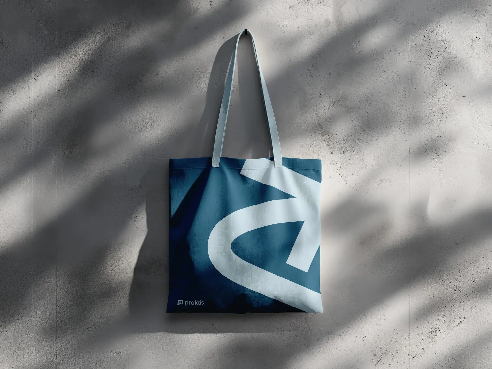A canvas tote bag hanging from the wall showcasing creative branding for the Praktis learning app
