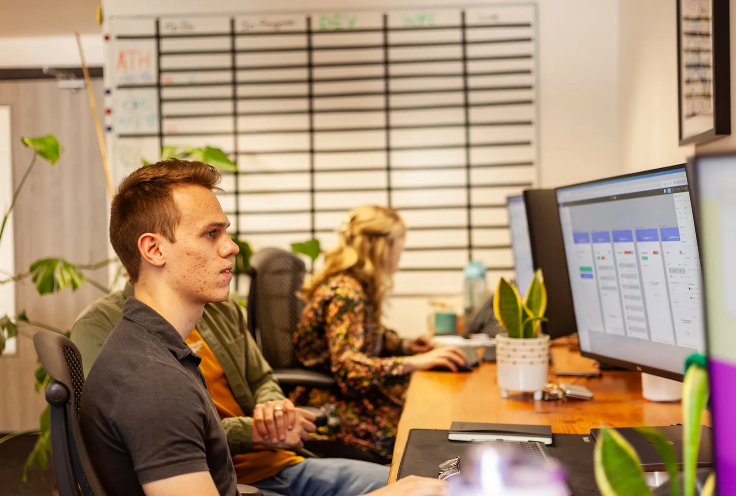 A man sitting at a desk looking at mobile prototypes on a phone