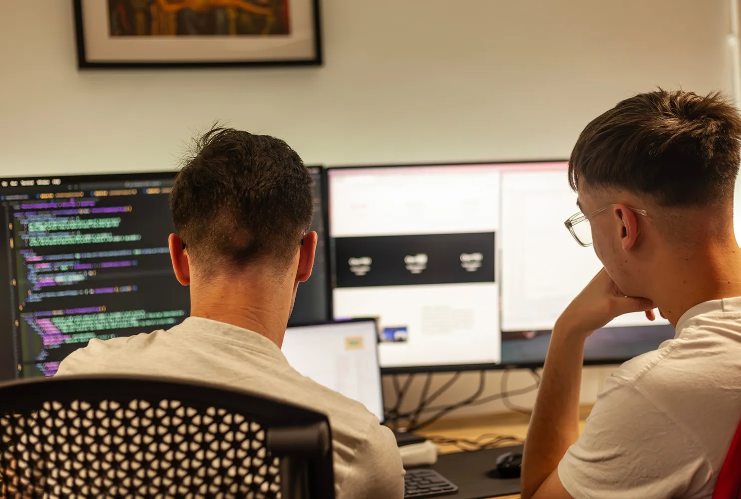 Two men sitting at a desk looking at computer screens