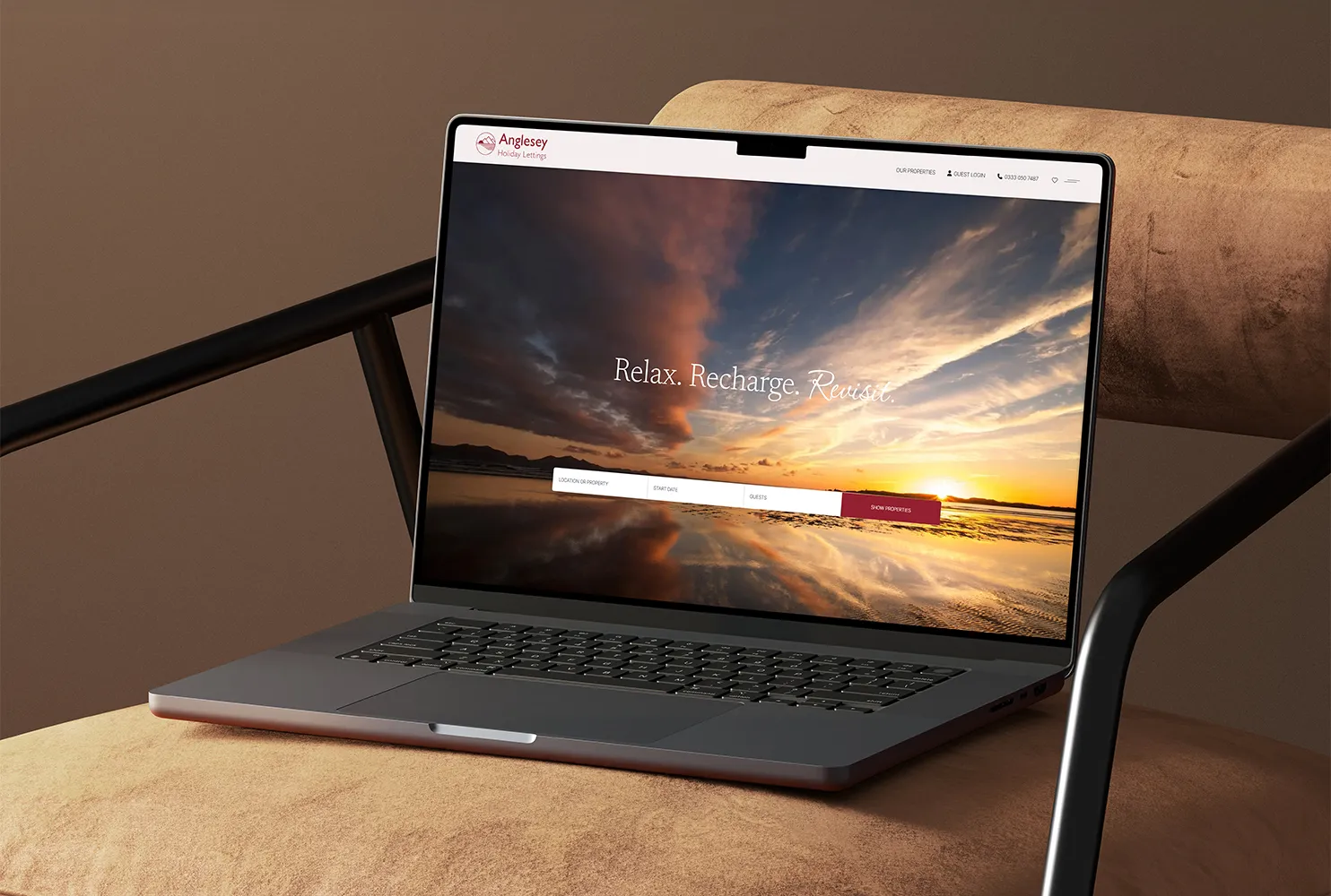 A Macbook on a leather chair showing the Anglesey Holiday lettings website homepage