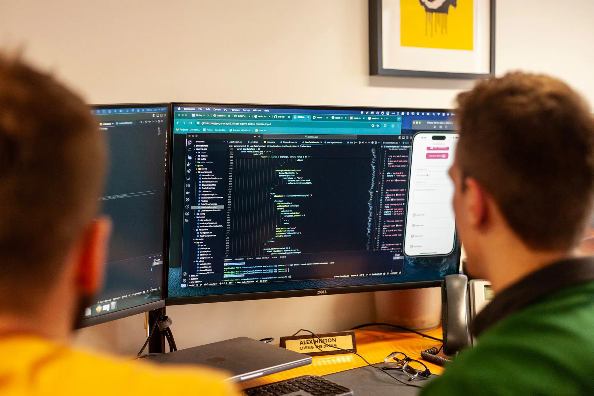 Two men working at a desk with dual monitors displaying code