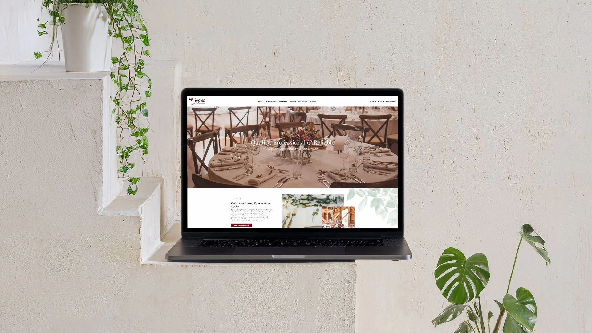 A MacBook displaying the Tipples website on a beige wall shelf with cascading green vines on the left and a Monstera plant on the right