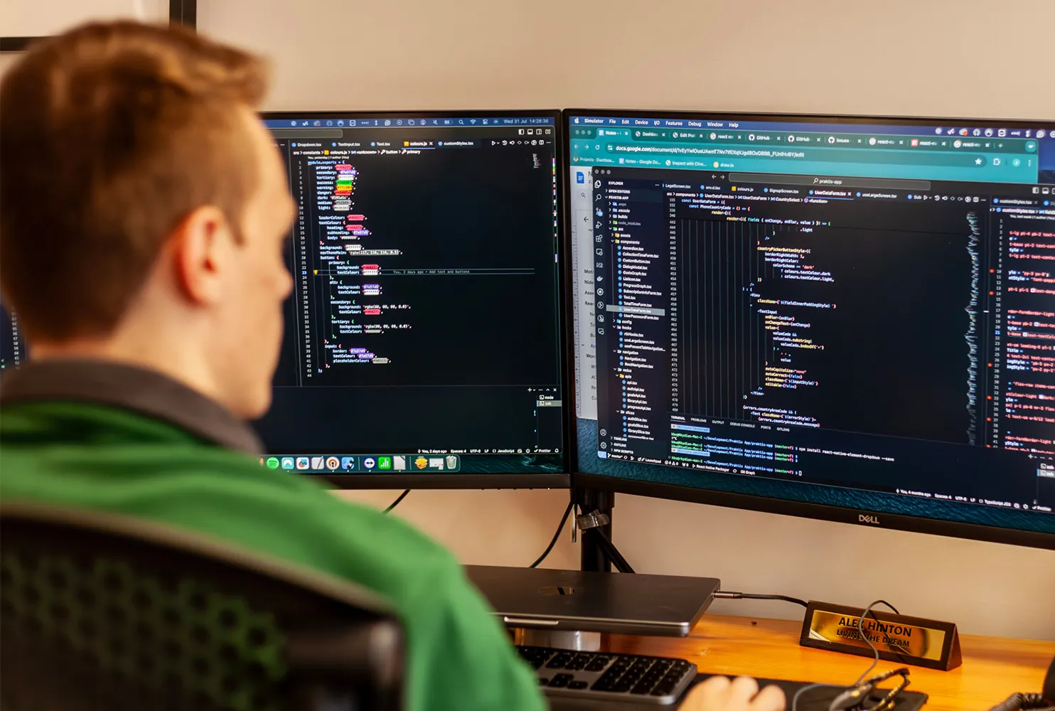 A man working at a desk with two monitors displaying code
