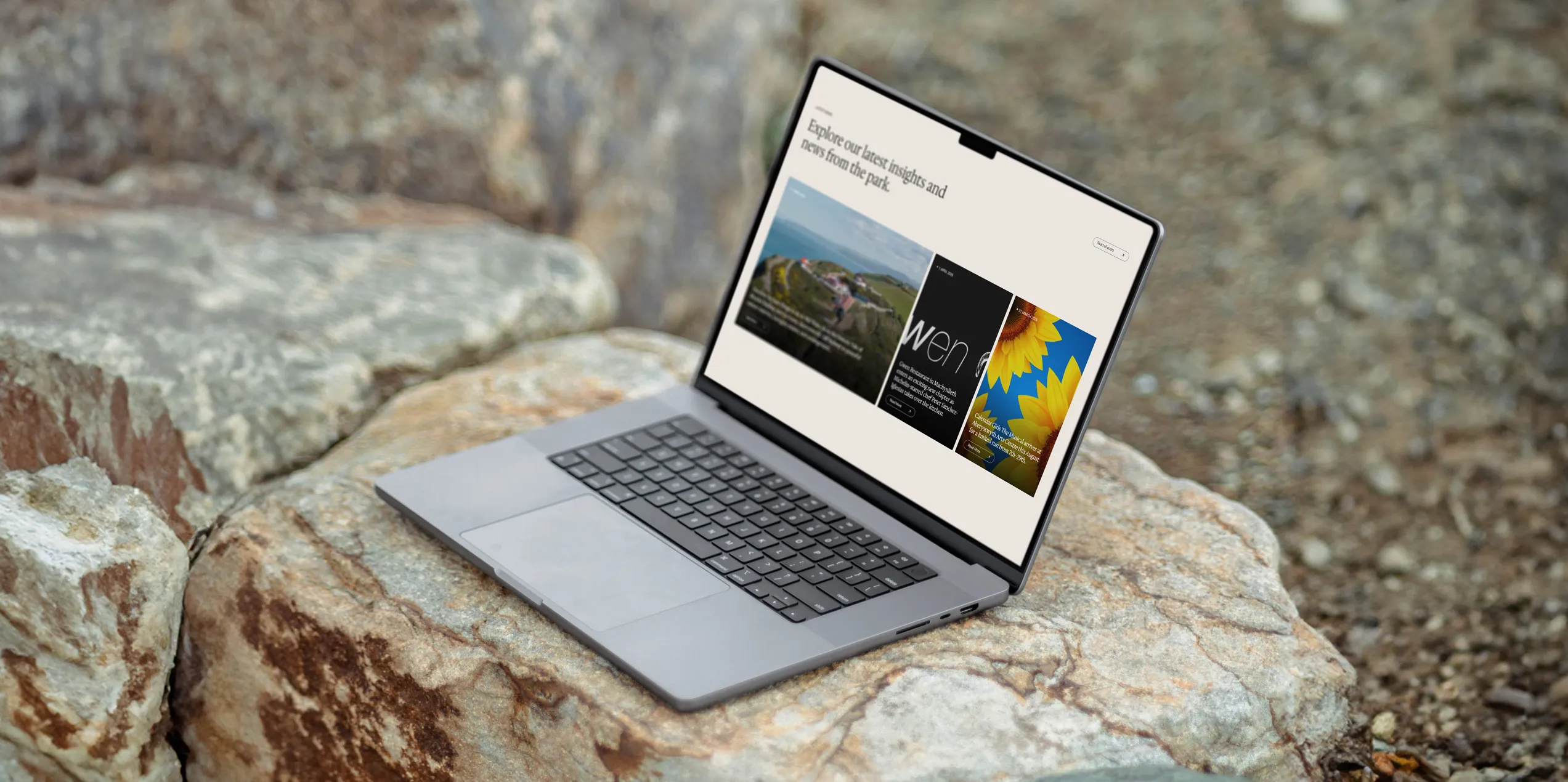 Open laptop on rocks displaying the Glanlerry blog section with vibrant images and text.